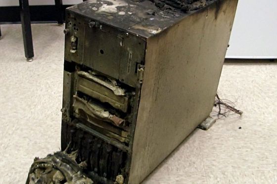 Ausgebrannter Server-Tower mit geschmolzenen Laufwerken auf einem Büroboden