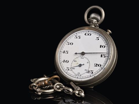 Alte mechanische Stoppuhr mit Kette vor schwarzem Hintergrund