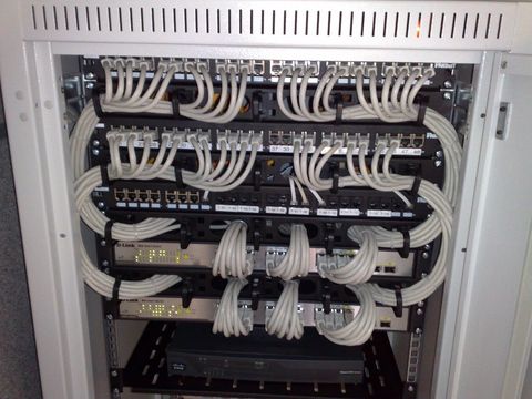 Netzwerkschrank mit Patchfeldern, grauen Netzwerkkabeln und zwei Switches