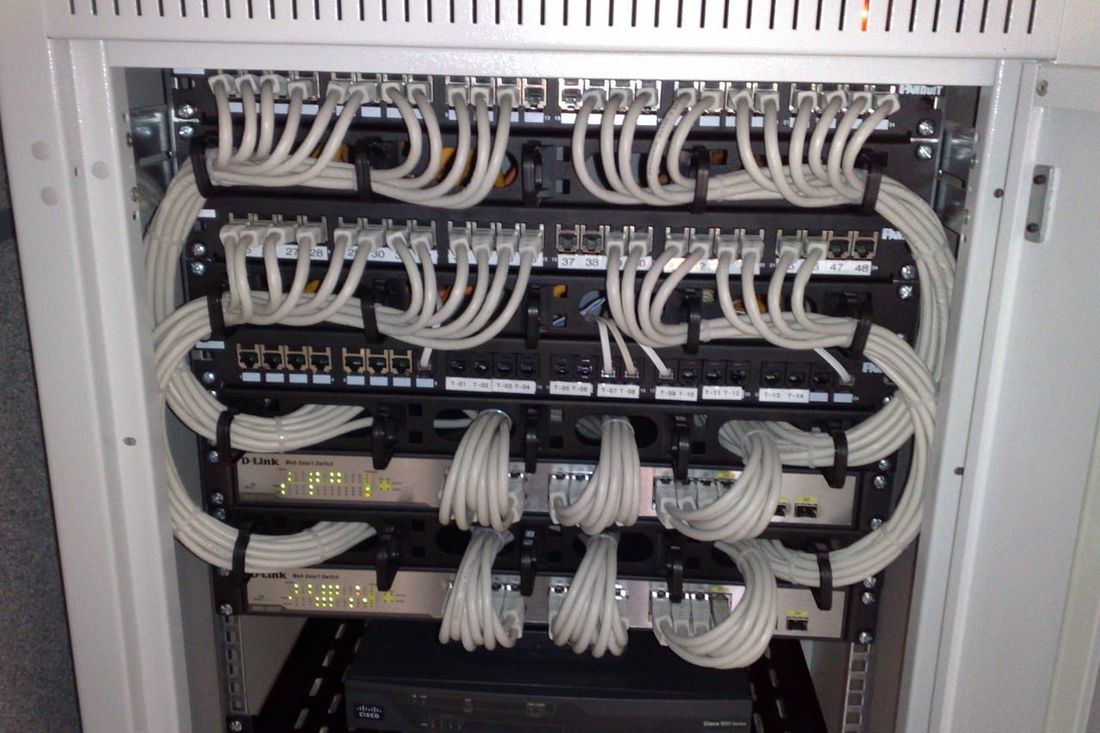 Netzwerkschrank mit Patchfeldern, grauen Netzwerkkabeln und zwei Switches